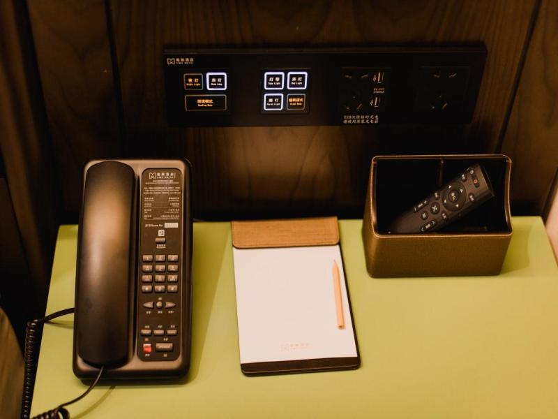 a desk with a phone and a remote control at GME Lu'an Yeji District Administrative Center Hotel in Lu'an
