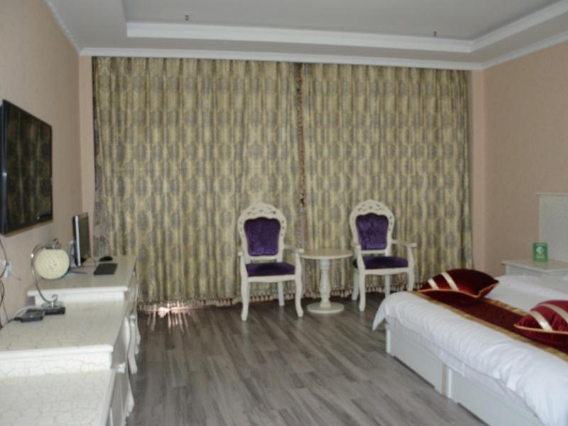 a bedroom with a bed and two chairs and a desk at Green Alliance Langfang Xianghe County Xiushui Street PengDa furniture city Hotel in Langfang