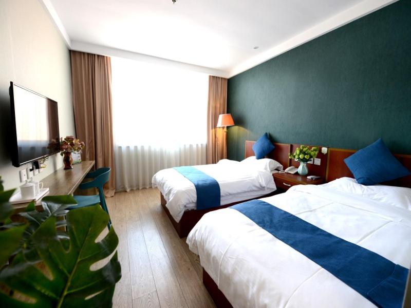um quarto de hotel com duas camas e uma televisão em Shell Yantaishan Park Hotel em Yantai