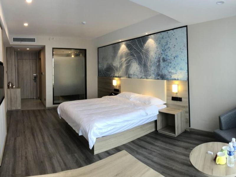 een slaapkamer met een bed en een groot schilderij aan de muur bij GreenTree Eastern Huai'an Railway Station Mandu Plaza Hotel in Huai'an