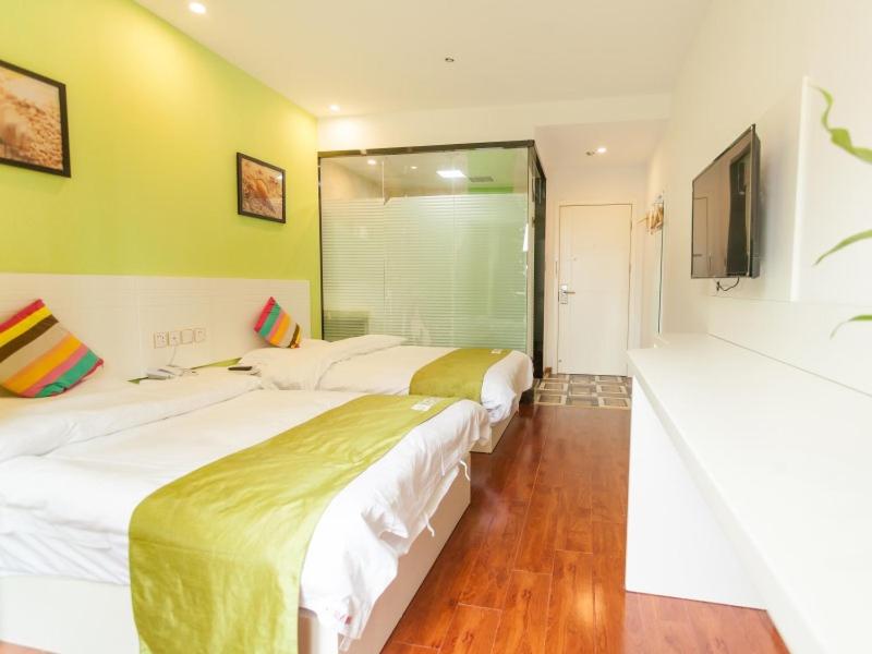 two beds in a room with yellow walls at Shell Hefei Economic Development Zone Hong Kong and Macao Square Hotel in Hefei
