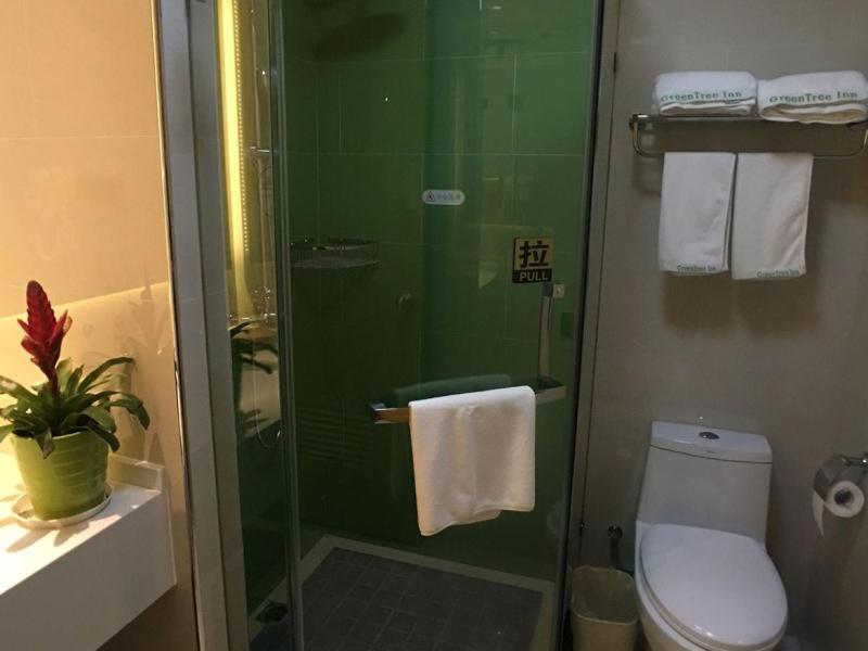 a bathroom with a shower with a toilet and towels at GreenTree Inn Shaoxing Binhai New City Dongsen Commercial Square Hotel in Shaoxing