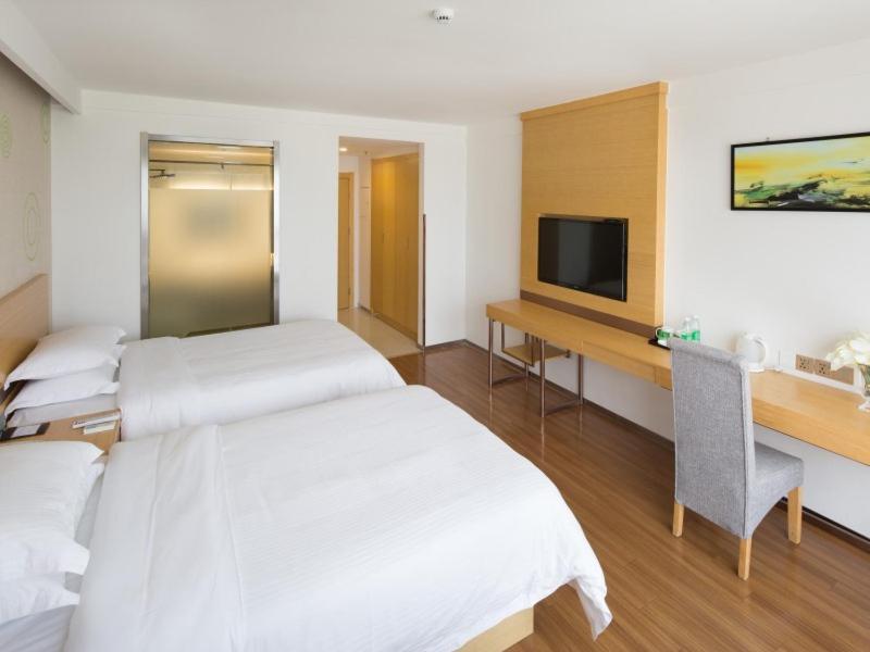 a hotel room with two beds and a desk with a television at GreenTree Inn Yancheng National Fitness Center Express Hotel in Yancheng