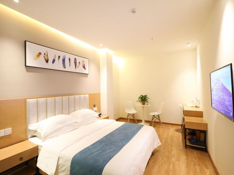 um quarto com uma cama, uma secretária e uma televisão em Shell Xinzheng Airport Port Huaxia Avenue Hotel em Xinzheng