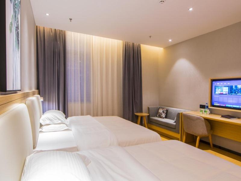 ein Hotelzimmer mit 2 Betten, einem Schreibtisch und einem TV in der Unterkunft GreenTree Inn Fuzhou South Railway Station Business Hotel in Fuzhou