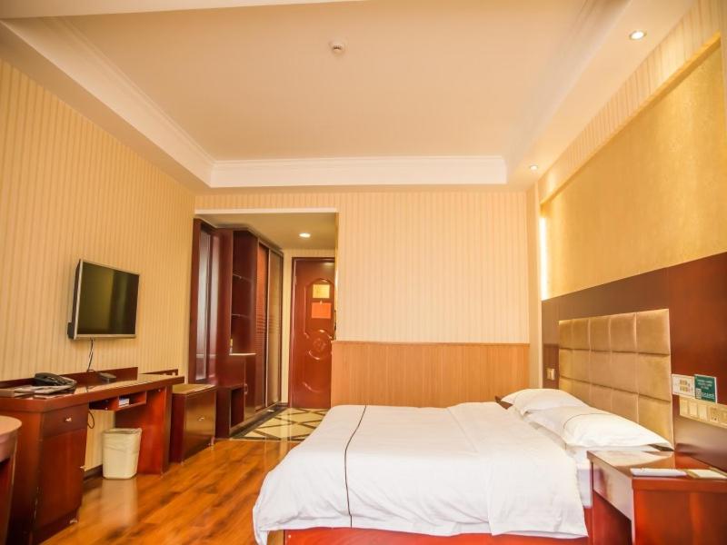Schlafzimmer mit einem Bett, einem Schreibtisch und einem TV in der Unterkunft GreenTree Inn Jiayuguan Xinhua South Road Express Hotel in Jiayuguan