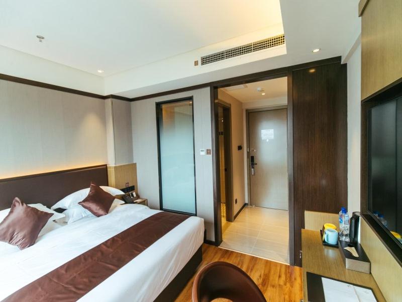 Habitación de hotel con cama y puerta corredera de cristal en GYA Langfang Art Avenue International Airport Hotel, en Langfang