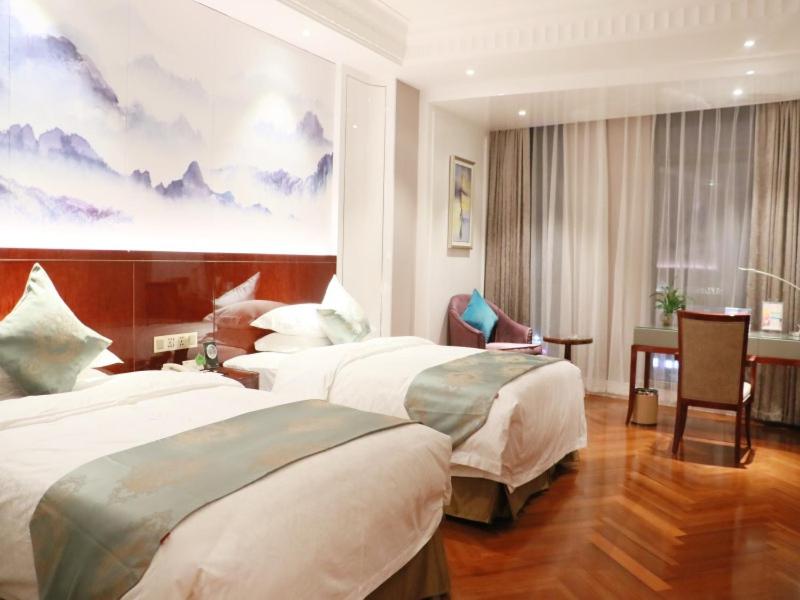 a hotel room with two beds and a desk at GreenTree Eastern Yancheng Jianhu County Aobaolia Life Plaza Hotel in Yancheng
