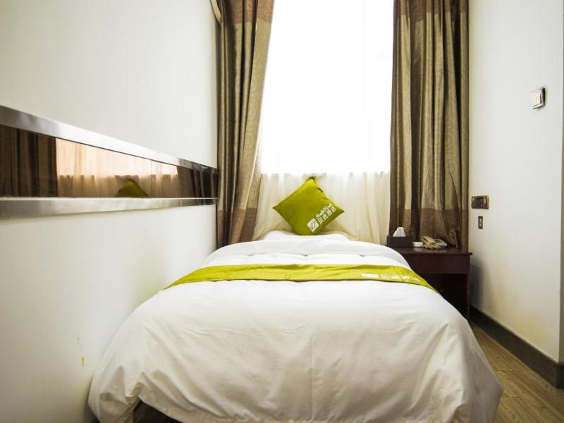 ein Schlafzimmer mit einem großen weißen Bett und einem grünen Kissen in der Unterkunft Shell Dingxi County Minzhou East Road Hotel in Min