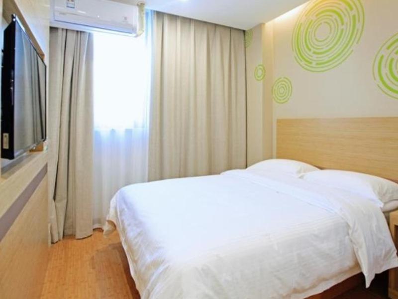 a bedroom with a white bed and a television at GreenTree Inn Anqing Duxiu Avenue Greenland Metropolis Express Hotel in Anqing