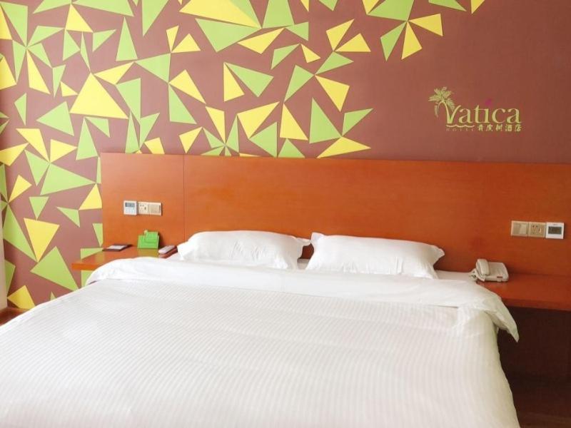 sypialnia z dużym białym łóżkiem i kolorową ścianą w obiekcie Vatica Fuyang Linquan County Tenghui International City Hotel w Fuyang