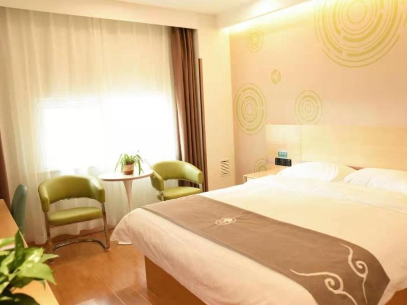 Habitación de hotel con cama, mesa y sillas en GreenTree Inn Baoding Gaobeidian Baigou Express Hotel, en Baoding