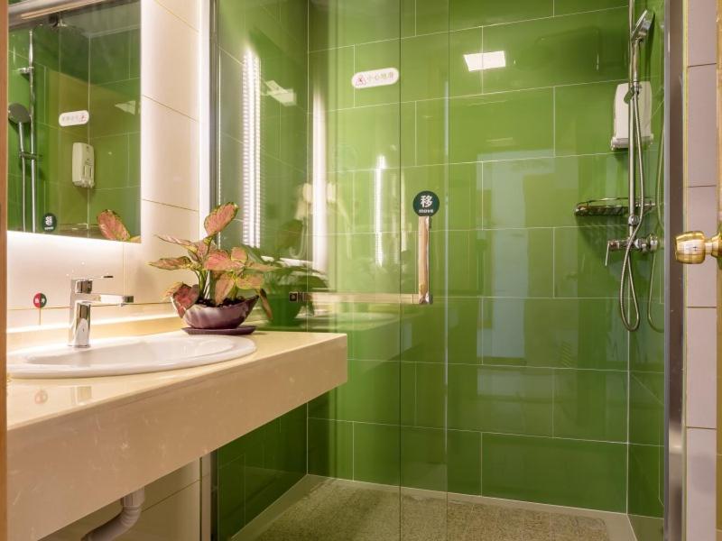 La salle de bains est pourvue de carrelage vert, d'un lavabo et d'une douche. dans l'établissement GreenTree InnChangZhou Wujin District Huangli Town Taoyuan Road Express Hotel, à Changzhou