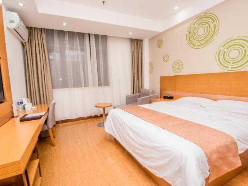 una camera d'albergo con un letto grande e una scrivania di GreenTree Inn Xuchang Yucheng County Ziyun Avenue Business Hotel a Xuchang