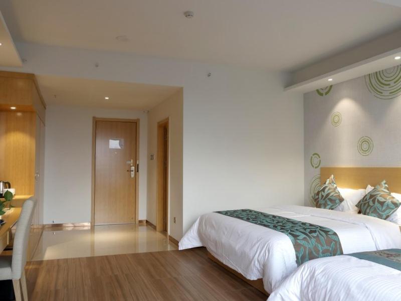 a hotel room with two beds and a hallway at GreenTree Inn Qionghai Boao Railway Station Business Hotel in Qionghai