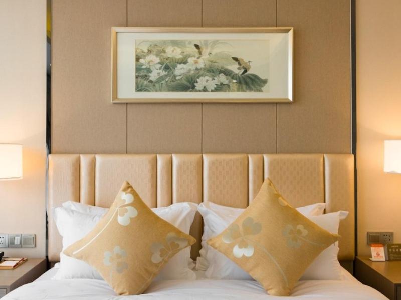 łóżko z poduszkami i zdjęciem na ścianie w obiekcie GreenTree Eastern Wuxi Xinwu District Airport Road Hotel w mieście Wuxi