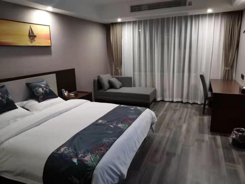 Habitación de hotel con cama grande y escritorio. en Shell Fuyang City South Bus Station Hotel, en Fuyang