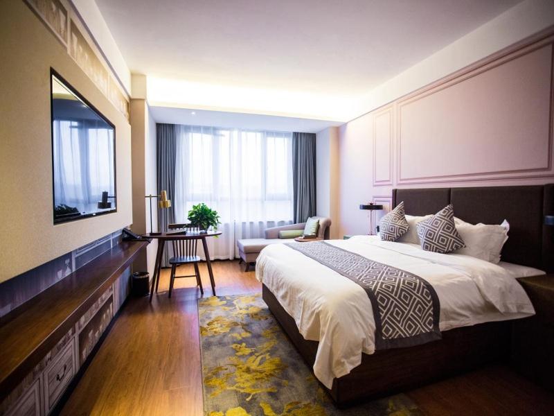 Cette chambre comprend un grand lit et une télévision. dans l'établissement Greentree Hotel Group Gme Luoyang City Longmen High Speed Railway Station University City Hotel, à Luoyang