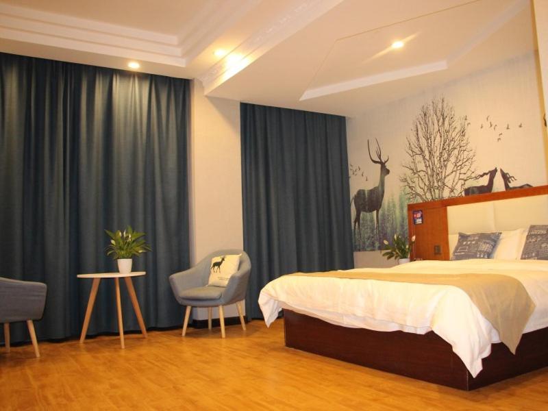 開封市にあるShell Kaifeng City Lancao County Women and Children Hospital Hotelのベッドと椅子付きのホテルルーム