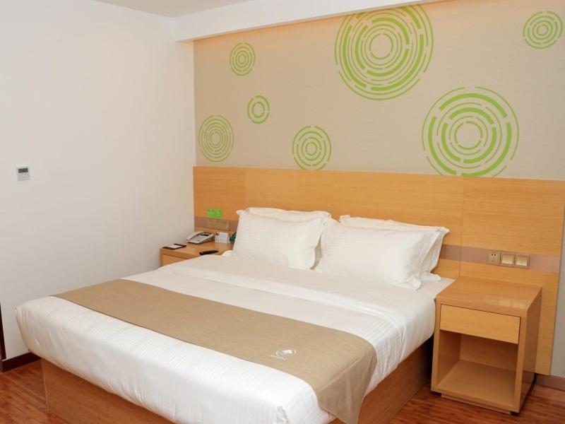 a bedroom with a large bed with white sheets at GreenTree Inn Huangshi Huahu Development Zone Daquan Road Business Hotel in Huangshi