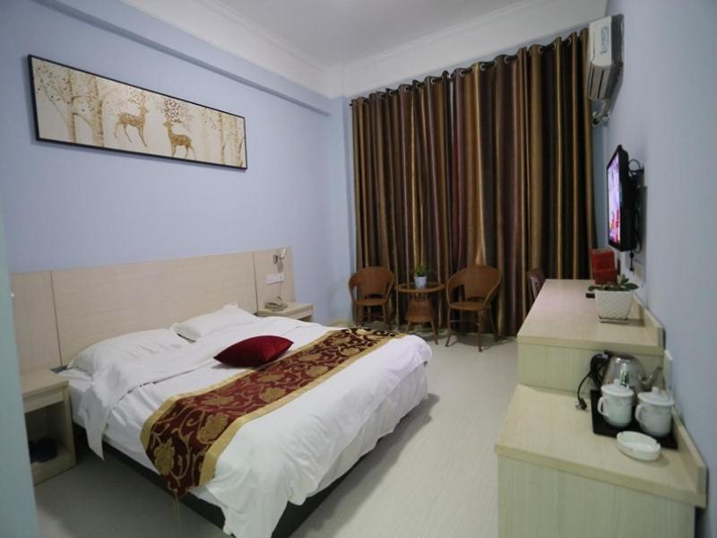 a hotel room with a large bed and a table at Shell Luoyang Lijingmen Mingtang Hotel in Luoyang