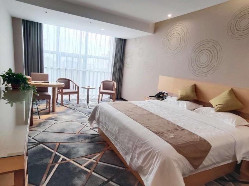 um quarto com uma cama grande, uma mesa e cadeiras em GreenTree Inn Huainan Shannan New District Erzhong Business Hotel em Sanhe