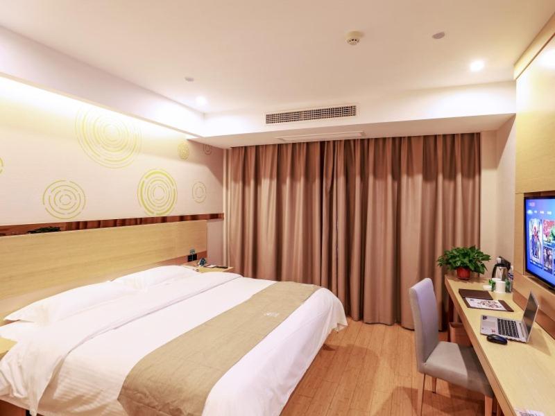 um quarto de hotel com uma cama e uma secretária com um computador em GreenTree Inn Wuxi Yixing High-speed Railway Station Dingshu Town Tongshu Road Express Hotel em Wuxi