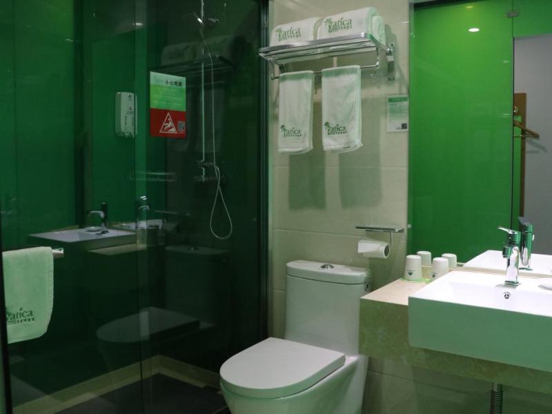 a green bathroom with a toilet and a sink at Vatica Hefei West Anqing Nongda East Gate Hotel in Hefei