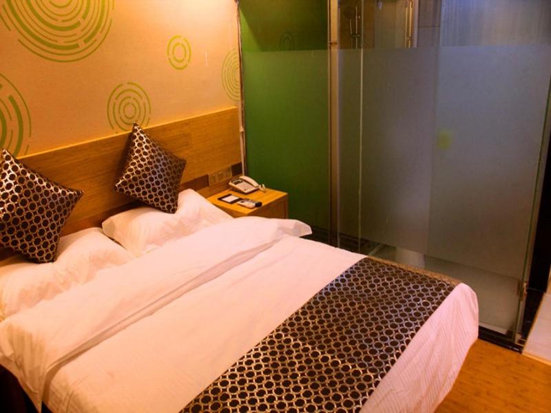 1 dormitorio con 1 cama y pared de cristal en GreenTree Inn Nanjing Provincial People's Hospital Express Hotel, en Nanjing