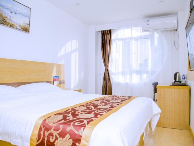 a bedroom with a large bed and a window at GreenTree Alliance Texas Railway Station Municipal Hospital Hotel in Dezhou
