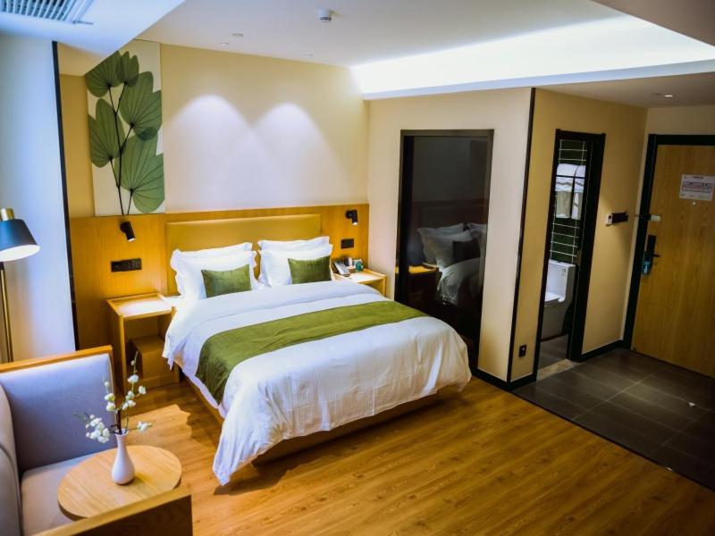 阜陽にあるGreenTree Inn Fuyang Century Fortune Plaza Business Hotelの大きなベッドとソファのあるホテルの部屋