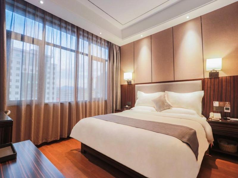 um quarto com uma cama grande e uma janela grande em GreenTree Eastern Ganzhou City Zhanggong DistrictEight one four Avenue bus station Hotel em Ganzhou