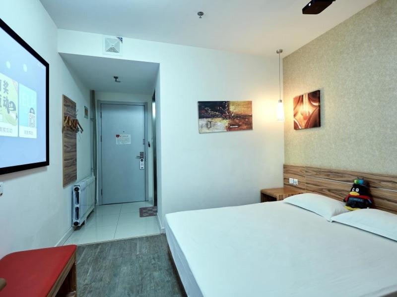 um quarto com uma grande cama branca e um ecrã de projecção em Shell Yantai Youth South Road Ludong University Hotel em Yantai