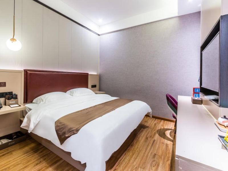 1 dormitorio con 1 cama blanca grande y escritorio en Gya Hangzhou Linan Qingshan Lake Science City Hotel, en Hangzhou