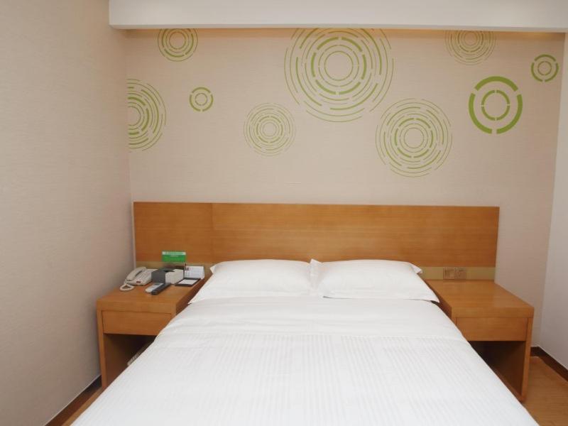 GreenTree Inn Hefei Huainan Road Huaihe Garden Express Hotel في خفي: غرفة نوم مع سرير أبيض كبير مع اللوح الأمامي الخشبي