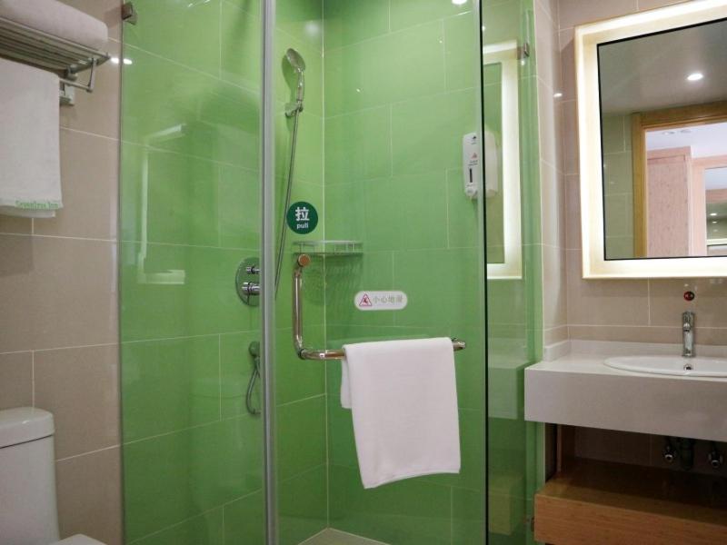 a green bathroom with a shower and a sink at GreenTree Inn Xuzhou Economic Development Zone Da Miaozhen Business Hotel in Xuzhou