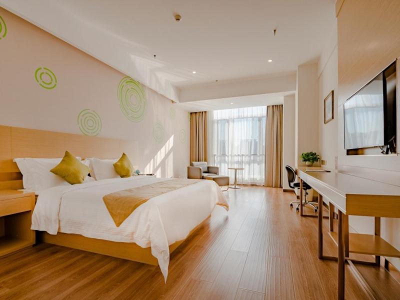 a bedroom with a large white bed and a desk at GreenTree Inn Taian High-speed Railway Station Lingshan Avenue Business Hotel in Tai'an