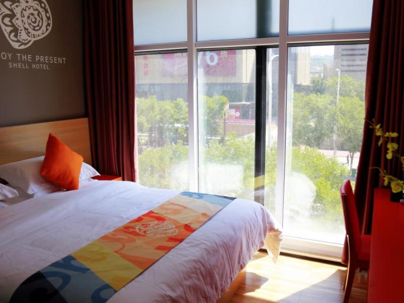 a bedroom with a bed and a large window at Shell Zhangjiakou City Qiaodong District Ginza Hotel in Zhangjiakou