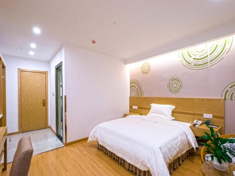 um quarto com uma grande cama branca e uma secretária em GreenTree Inn Anshun Xihang Road Business Hotel em Anshun