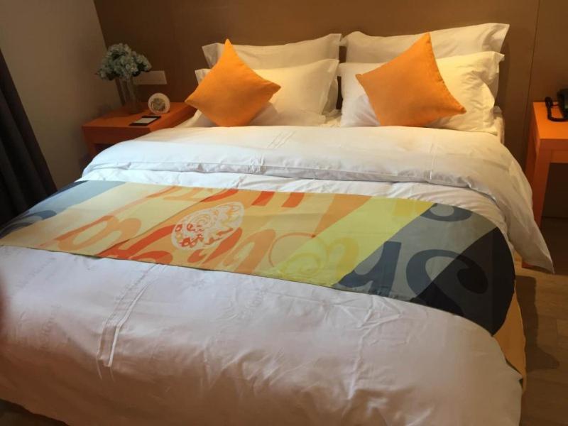 a bed with a colorful blanket on top of it at Shell Tai'an Taishan District Xinhuacheng International Plaza Hotel in Tai'an