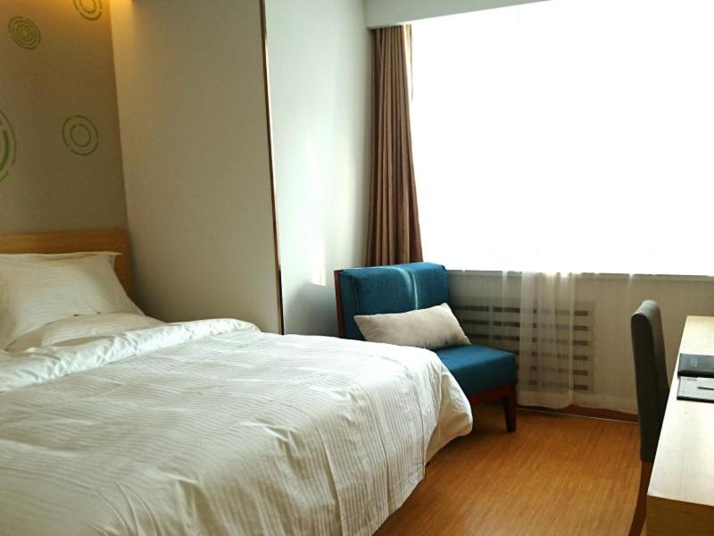 1 dormitorio con 1 cama y 1 silla azul en GreenTree Inn Shenyang Shenhe District Shenyang Station(N)Expreess Hotel, en Shenyang