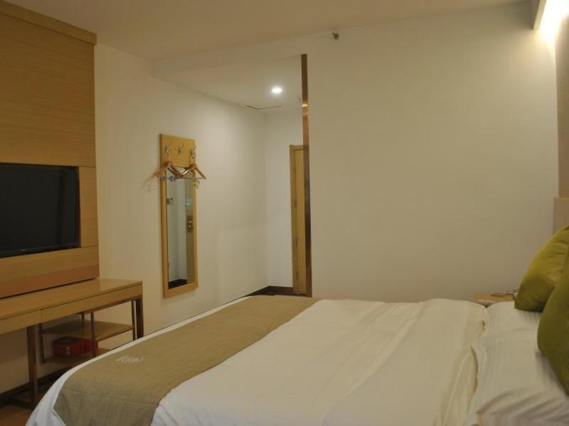 a bedroom with a bed and a flat screen tv at GreenTree Heze Changcheng Road Tianhua E-commerce Logistics Park Express Hotel in Heze