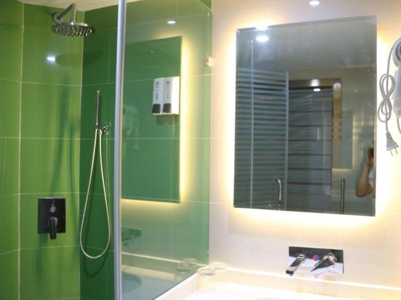 a bathroom with a shower and a sink with a mirror at GreenTree Inn Zhangye Liangjiadun Town Zhangnin Road Hotel in Zhangye