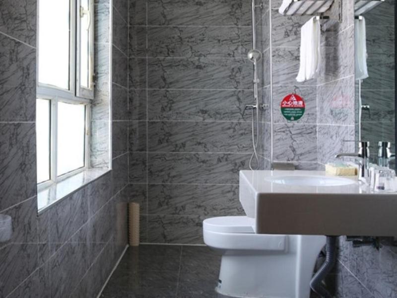 a bathroom with a sink and a toilet and a window at GreenTree Wulumuqi Airport Hotel in Ürümqi