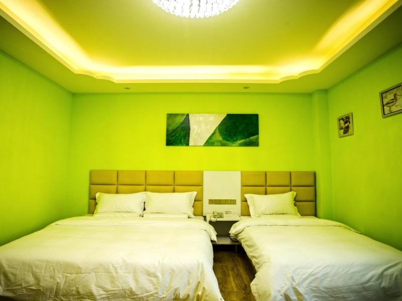two beds in a room with green walls at Shell Taiyuan City Xiaodian District Kangning Street Foxconn Hotel in Taiyuan
