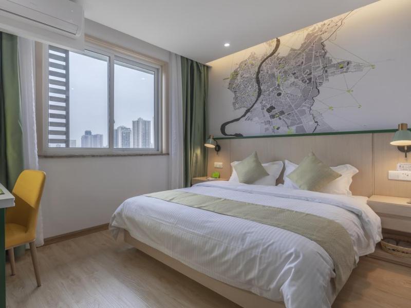 ein Schlafzimmer mit einem großen Bett mit einer Karte an der Wand in der Unterkunft Vatica Hefei Huangshan Road Yuexi Road Hotel in Hefei