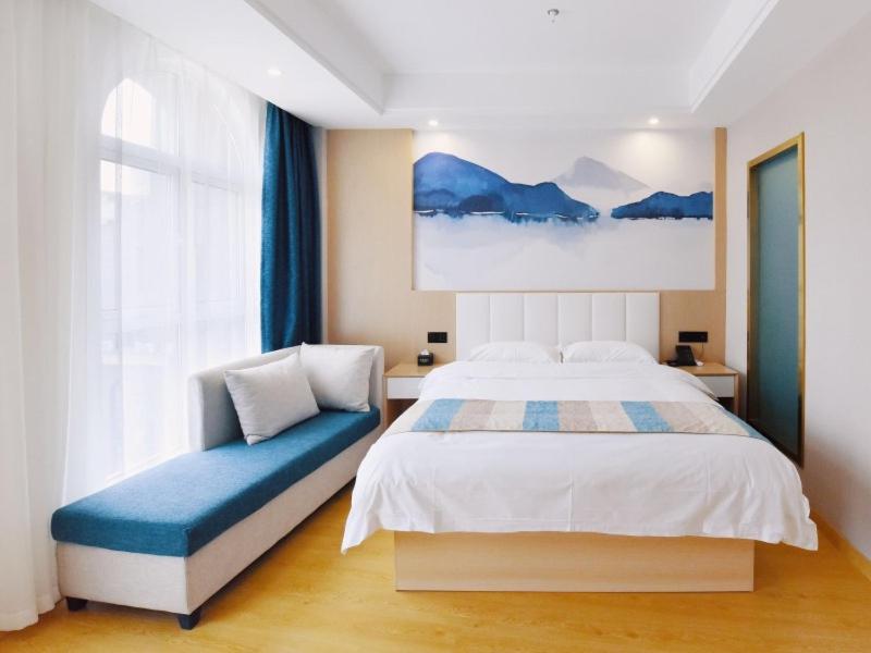 a bedroom with a bed and a blue bench at VX Wuxi Jiangyin High-tech Zone Panlongshan Park Hotel in Jiangyin