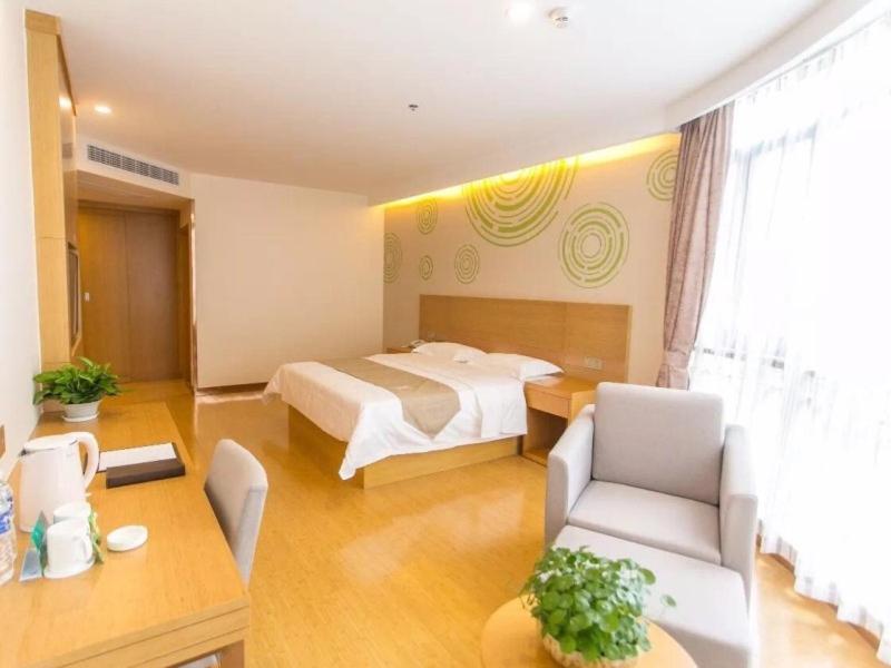 a bedroom with a bed and a living room at GreenTree Inn Jinan Jiyang Bus Station Express Hotel in Jiyang