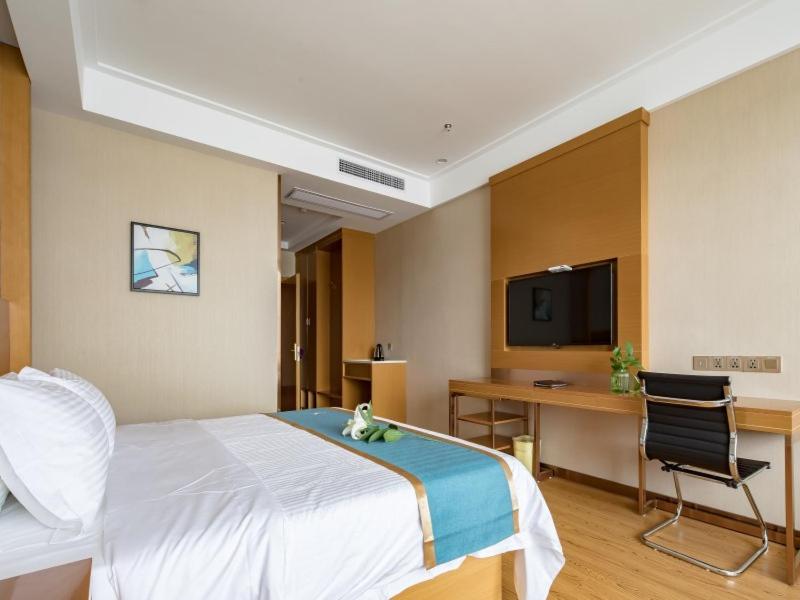 a bedroom with a bed and a desk and a tv at GreenTree Inn Wuxi Jiangyin City Renmin East Road Liangchen Square Business Hotel in Jiangyin