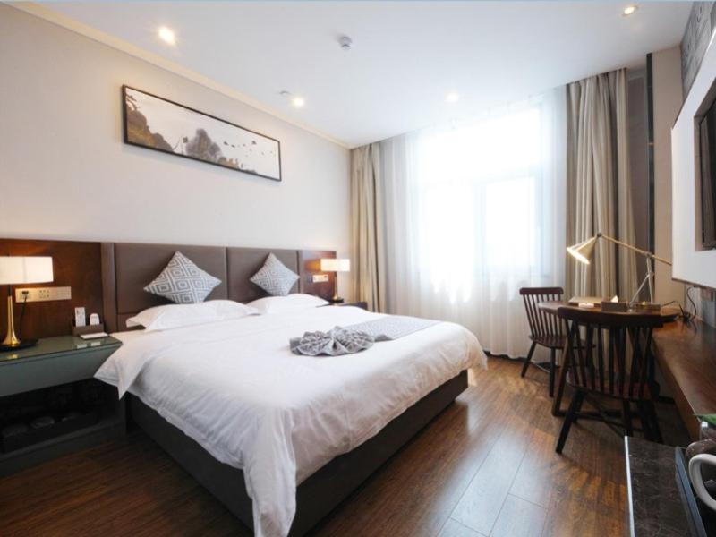 a bedroom with a large bed and a table and chairs at GME Hefei Feidong county High Speed Railway Station Longquan East Road Hotel in Hefei